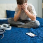 Sad,Teen,Boy,Covering,Face,With,Hands,After,Receiving,Bad